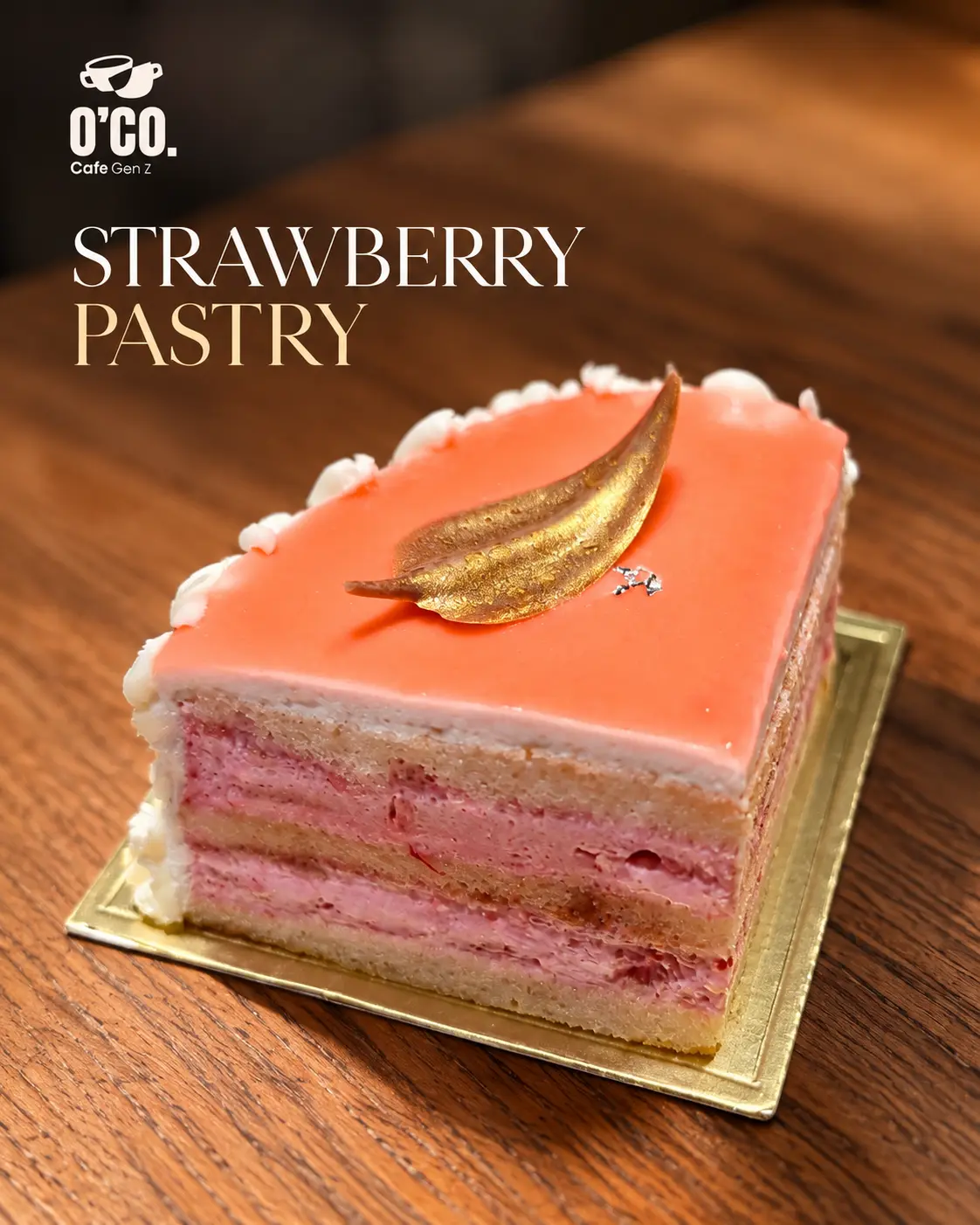 A layered strawberry pastry with a gold leaf on a wooden table at O’Co